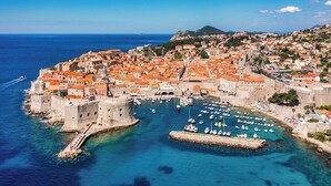 A coastal city with historic architecture, a harbor with boats, and a clear blue sea. - Dubrovnik Delight: A Sun-Kissed Sailing Experience (Komolac)