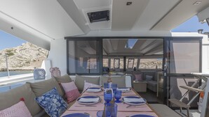 En matplats på ett fartyg med ett bord för fyra personer, bekväma sittplatser och utsikt över havet och det steniga landskapet.