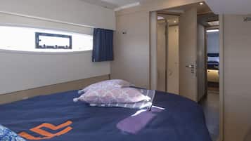Una camera da letto con un letto, cuscini, una finestra e una porta che conduce a un'altra stanza.