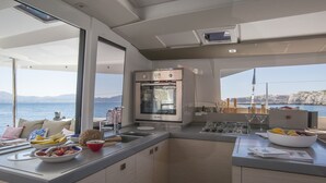 Ett modernt kök med en inbyggd ugn, en diskho och en matplats med utsikt över havet.