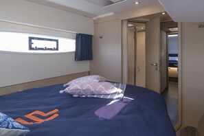 Ein Schlafzimmer mit einem Bett, Kissen, einem Fenster und einer Tür zu einem anderen Raum.