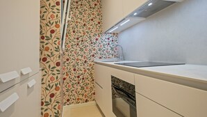 A modern kitchen with white cabinetry, a stainless steel sink, and a patterned backsplash.