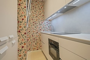 A modern kitchen with white cabinetry, a stainless steel sink, and a patterned backsplash.