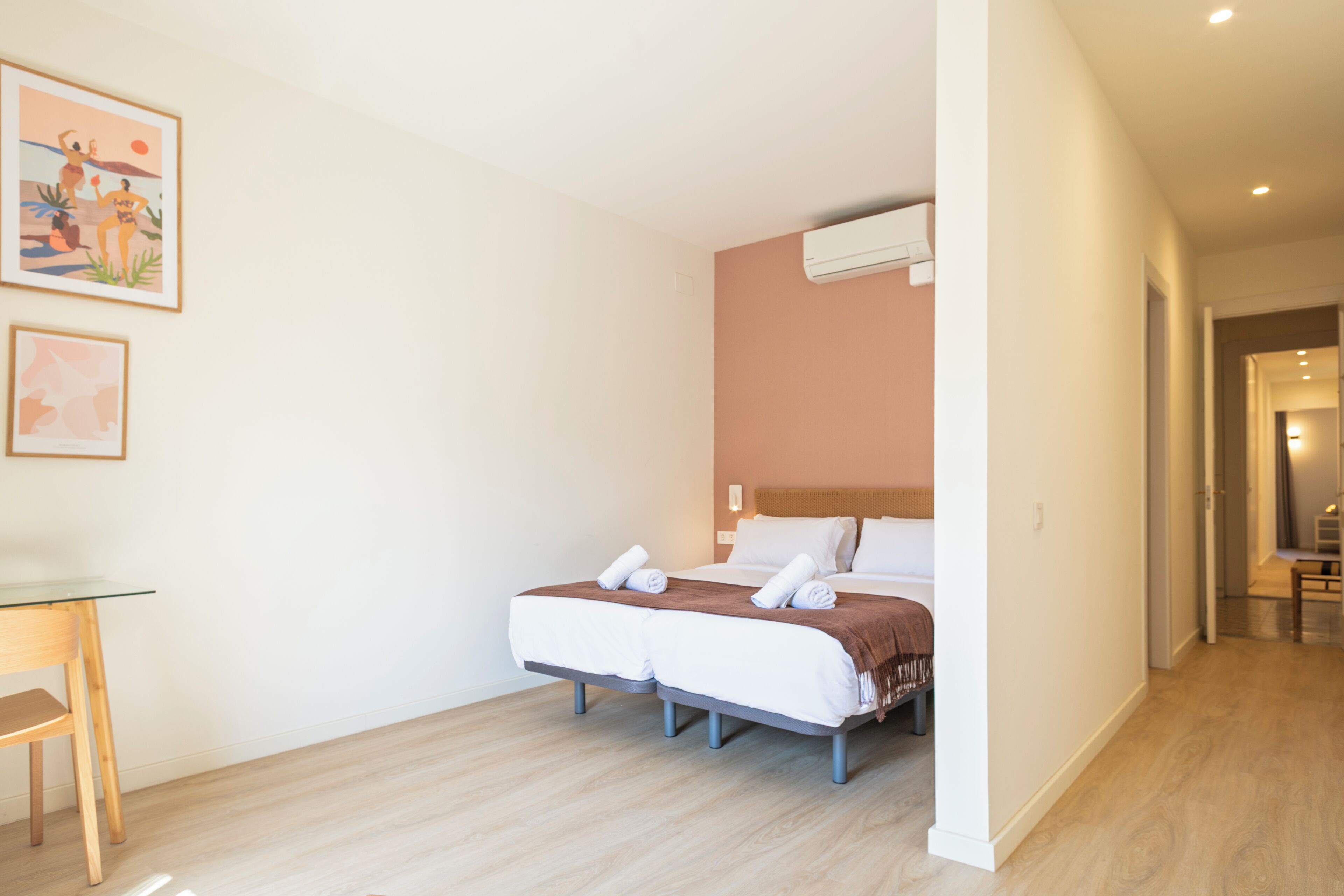 Una habitación de hotel con una cama, un escritorio y dos cuadros en la pared.