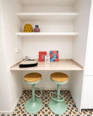 A kitchen area with two stools, a shelf with kitchenware, and two cookbooks. - Bonavista Apartments - Tamarit (Barcelona)