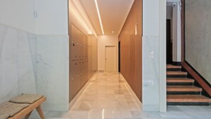 A modern hallway with lockers, a bench, and a staircase.