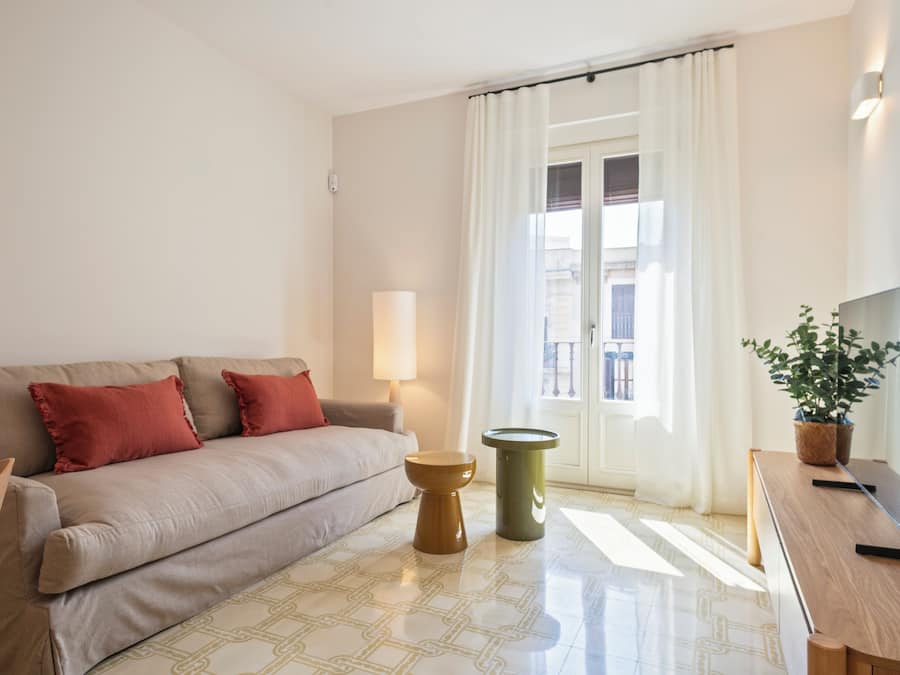 Una sala moderna con un sofá, una mesa de centro, una mesita auxiliar, una lámpara, un televisor y una planta en maceta.