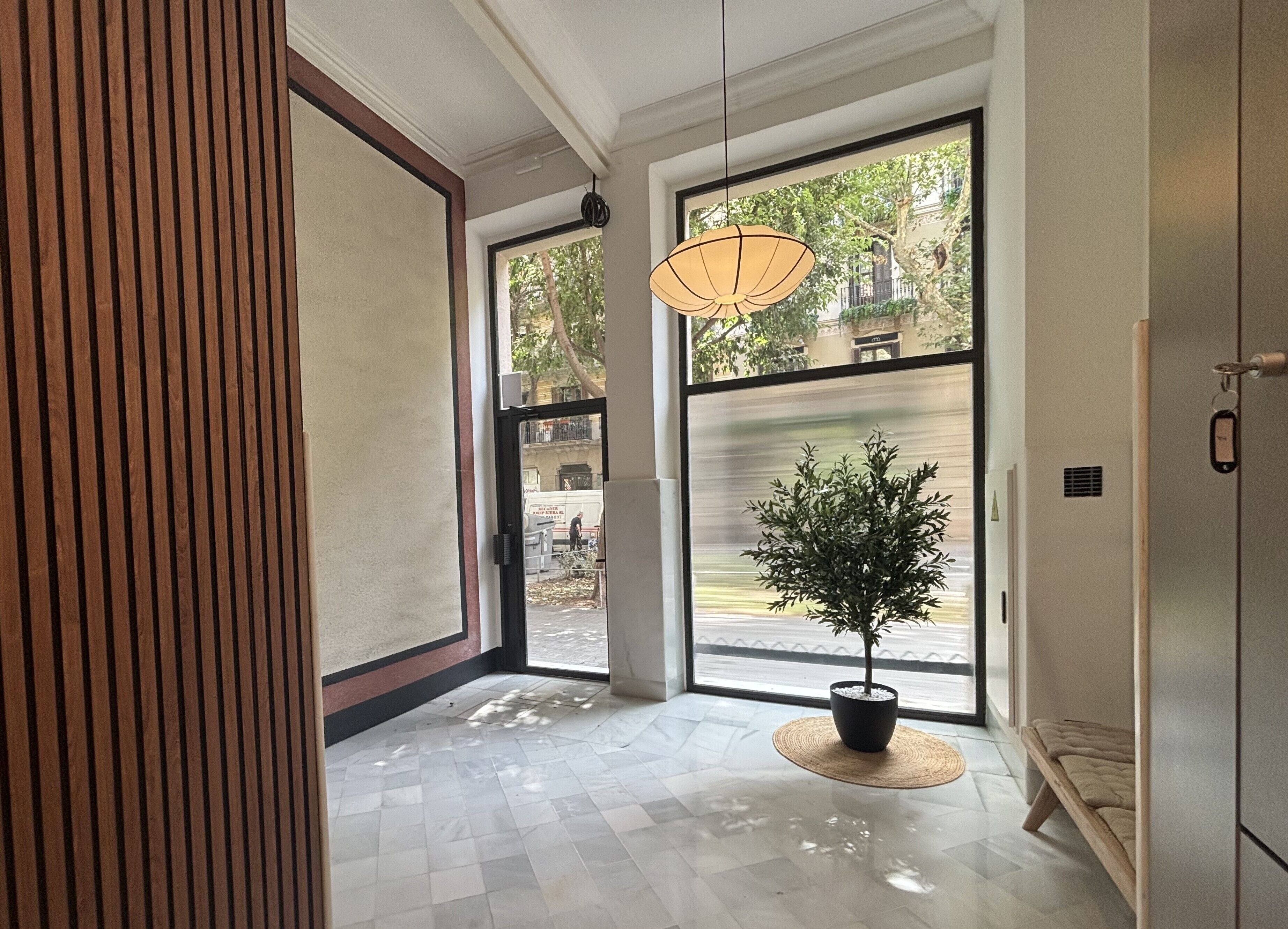 Un interior moderno con un amplio ventanal, una lámpara colgante y una planta en maceta.