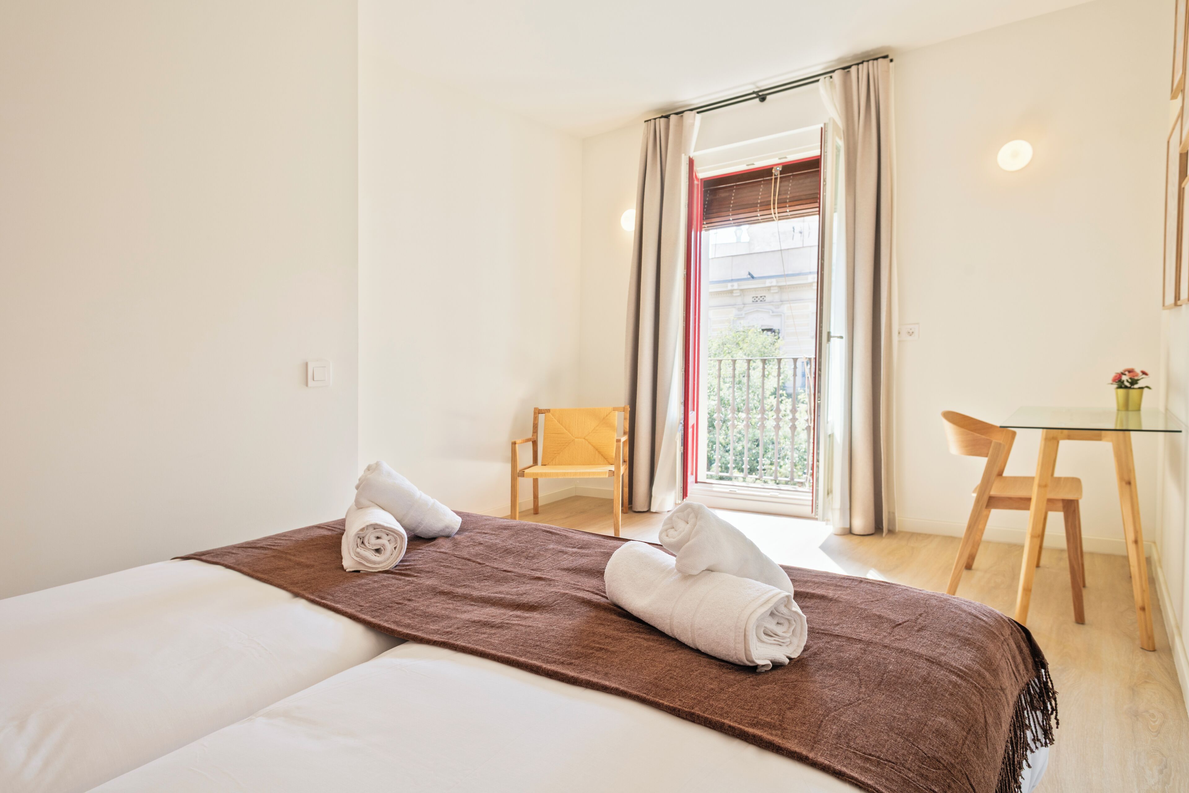 Een hotelkamer met een bed, een klein tafeltje, een stoel en een balkon met uitzicht.