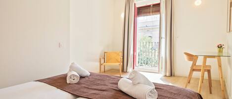Habitación de hotel con cama, una mesita, una silla y balcón con vistas.
