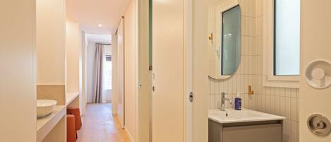 Een moderne badkamer met een witte wastafel, een spiegel en een handdoekhouder.