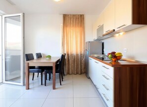 A modern kitchen with a dining area, a refrigerator, and a fruit bowl on the counter. - One-bedroom apartment Grey Goose 12 with private balcony (Novalja)