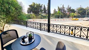 A balcony with a table and chairs, a railing, and a view of a road with cars.