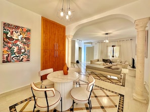 A spacious living area with a dining table, chairs, a sofa, and a large artwork on the wall. - GOLDEN TULIP APT SPACIEUX AVEC DEUX TERRASSES (La Marsa)