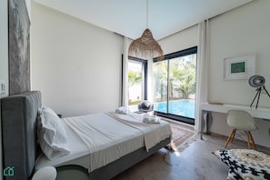 Une chambre moderne avec un lit, un bureau, une chaise et une vue sur une piscine.
