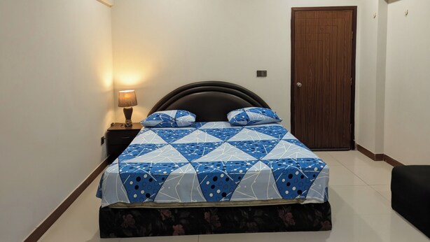 A bedroom with a bed, a nightstand, a lamp, and a door.