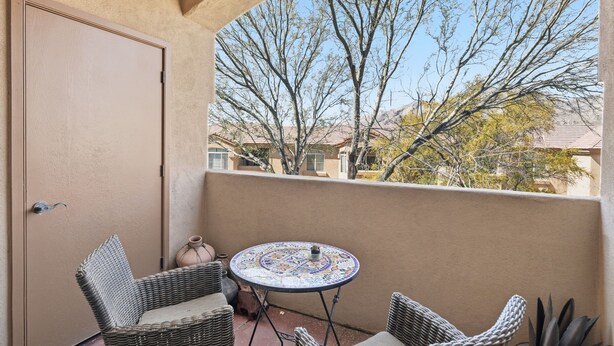 A balcony with wicker chairs, a small table, and a view of trees and buildings. - 2nd floor includes many personal touches and upgrades making a Perfect rental (Tucson)