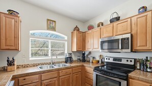 A kitchen with wooden cabinets, a stainless steel stove, a microwave, and a window with blinds. - 2nd floor includes many personal touches and upgrades making a Perfect rental (Tucson)