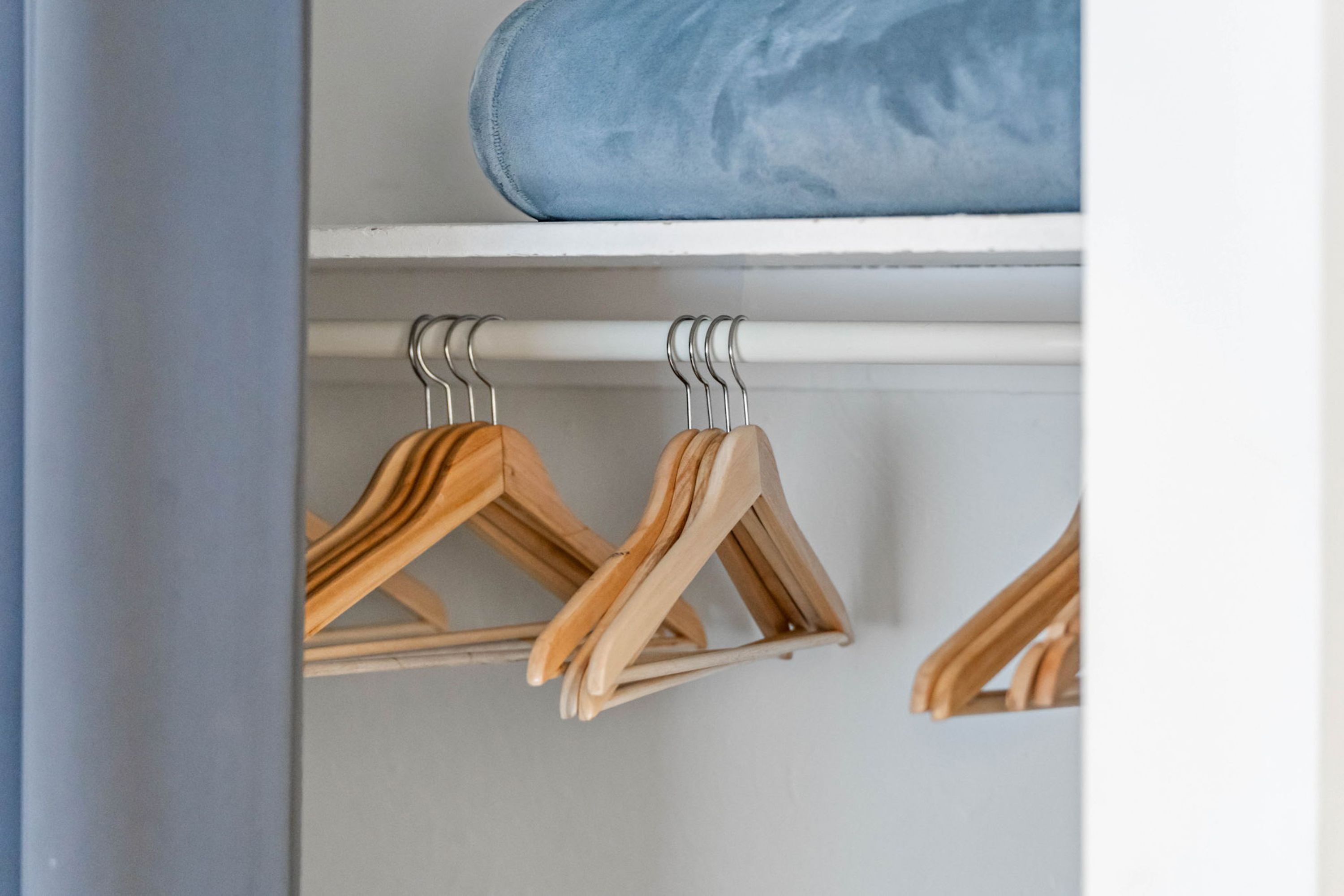 A closet with wooden hangers and a blue storage box.