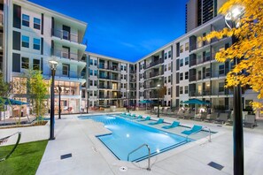 A modern hotel with a central swimming pool, outdoor seating, and a well-lit courtyard. - (S1BC) Great Location, Peaceful 1-BR Near Colony Square (Atlanta)