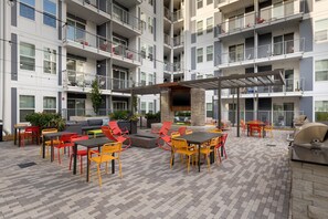 A multi-story residential building with outdoor seating areas, including tables and chairs, and a barbecue grill. - (S1BC) Great Location, Peaceful 1-BR Near Colony Square (Atlanta)