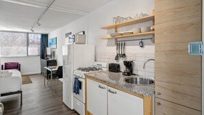 Eine kleine Küche mit weißen Schränken, einer Arbeitsplatte aus Granit und Holzregalen über der Spüle.