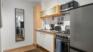A compact kitchen with white cabinets, a stainless steel refrigerator, a microwave, a stove, and a coffee maker. - (CPH) Secluded Studio Safe, Serene, and Serviced (Atlanta)