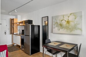 A modern kitchen with a black refrigerator, wooden cabinets, and a dining area with a table and chairs. - (CPB) Quiet Studio Perfect for Travel Nurses (Atlanta)