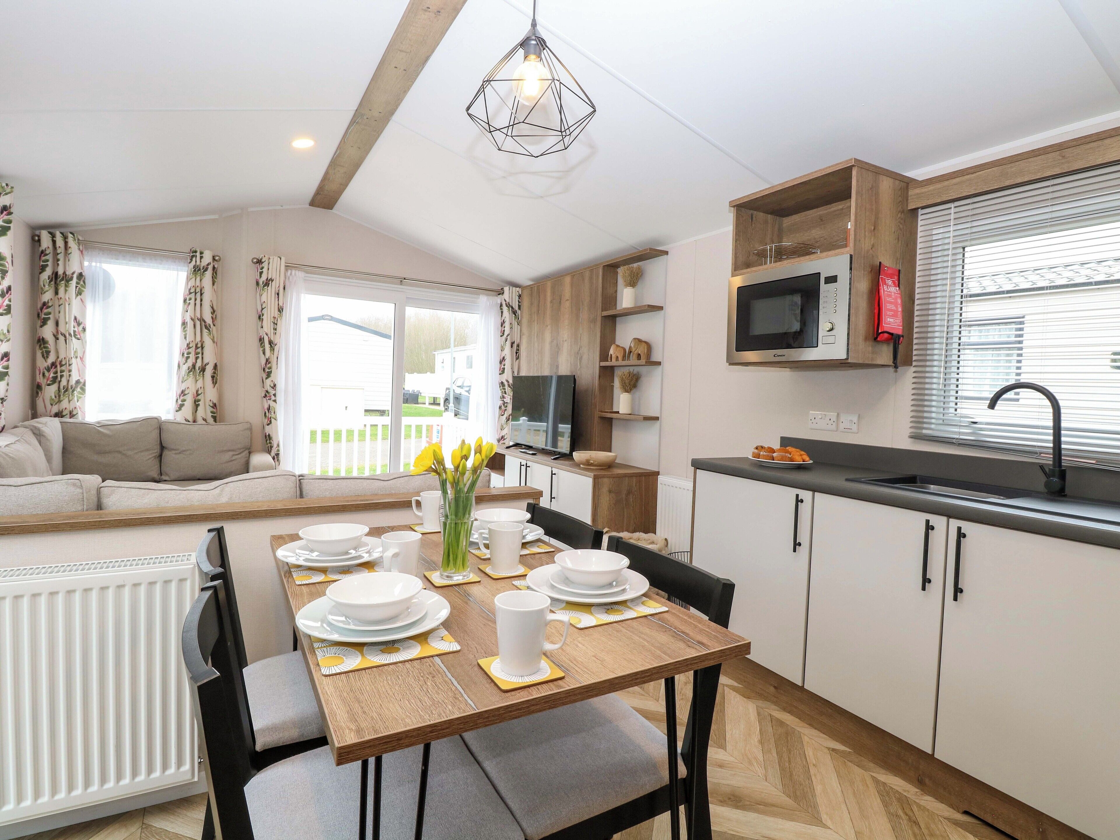 A modern kitchen with a dining table set for four, a microwave, and a sink.