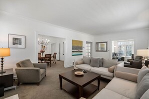 A spacious living room with a sofa set, a coffee table, and a dining area with chairs and a chandelier. - (SH) Rare Serviced 3-BR in Secluded and Peaceful Neighborhood (Atlanta)