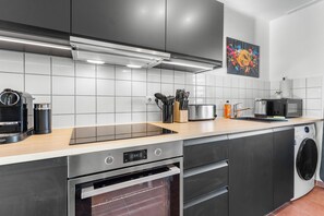 Eine moderne Küche mit Edelstahlgeräten, einer Holzausziehtheke und einer gefliesten Spritzschutzwand.