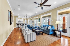 A spacious living room with a blue sectional sofa, striped armchairs, and a wooden floor. - Sailor's Cove by Lake Martin Vibe, 3 bedrooms, 2.5 baths, pets ok! (Dadeville)