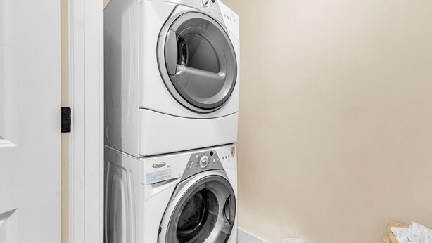 Lavadora y secadora apiladas en una habitación con paredes color beige.