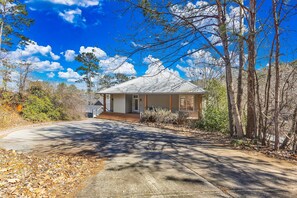 A single-story house with a porch, surrounded by trees and a clear sky.