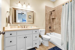 A bathroom with a white vanity, a large mirror, a toilet, a bathtub, and a shower.