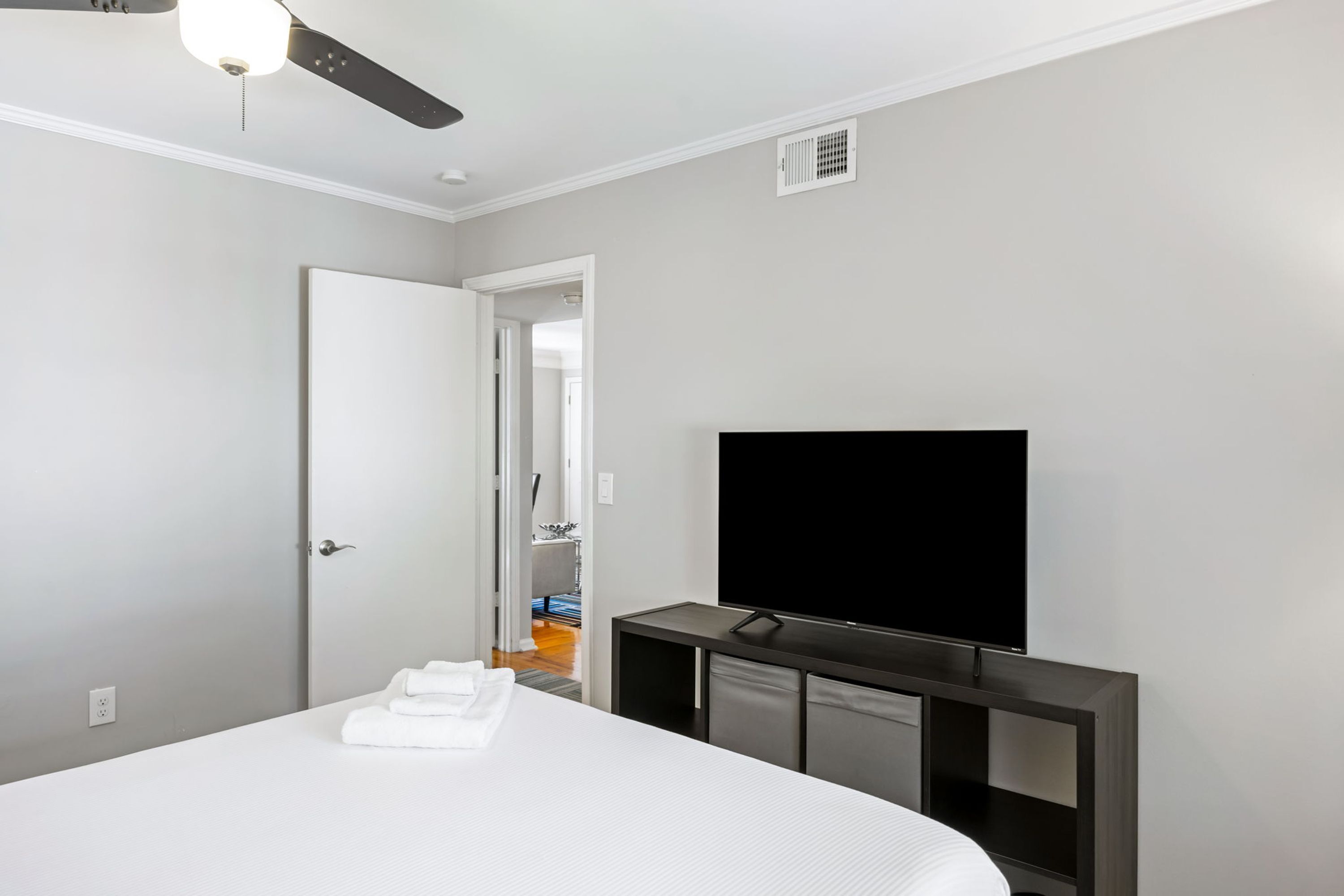 Une chambre d’hôtel équipée d’un lit, d’une télévision, d’un ventilateur de plafond et d’une porte donnant accès à une salle de bain.