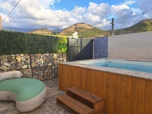 A wooden hot tub with a stone wall and a green cushioned seating area. - House with a private pool (calenzana)