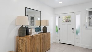 A reception area with a wooden console, two lamps, a mirror, and a door with frosted glass panels. - Sunny Terrace • Pool  Hot Tub • B-Ball CT•  Near Busch Gardens & USF • Sleeps 10 (Tampa)