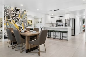 Una cocina moderna con armarios blancos, electrodomésticos de acero inoxidable y una isla central con taburetes de bar.