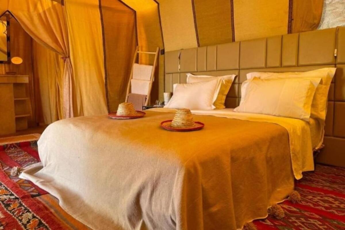 Quarto com uma cama, mesa de cabeceira, luminária e janela com cortinas.