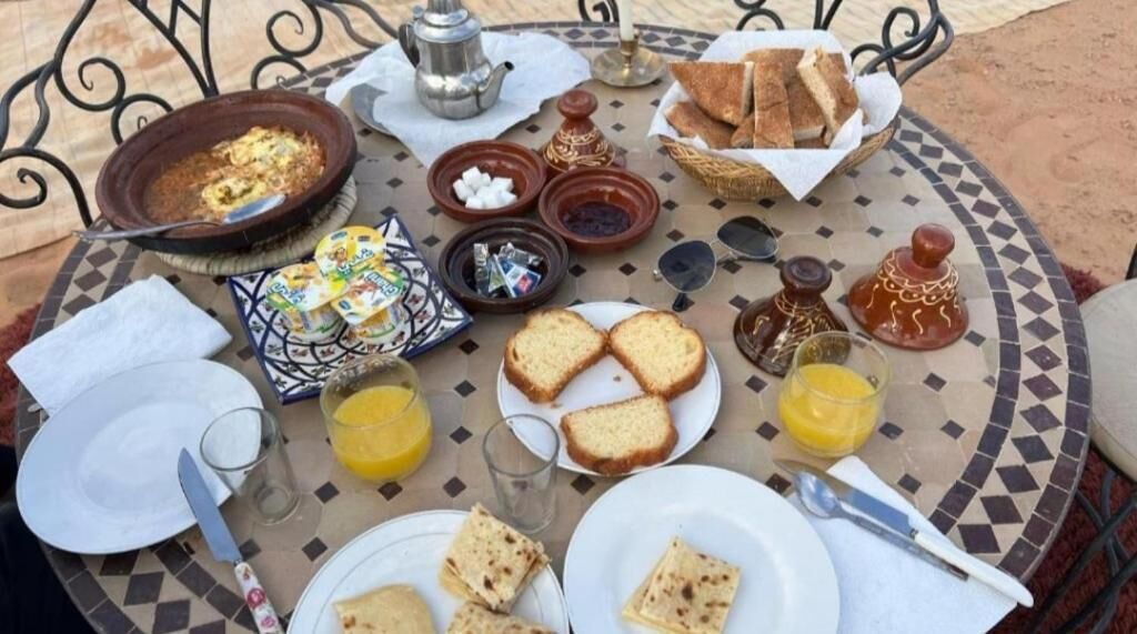 A breakfast setup with bread, eggs, and orange juice on a tiled table.