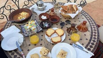 A breakfast setup with bread, eggs, and orange juice on a tiled table.