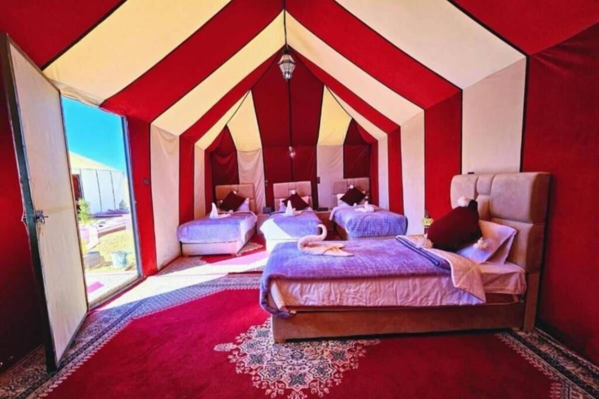 Um quarto em estilo tenda com duas camas, esquema de cores vermelho e branco e um tapete estampado.