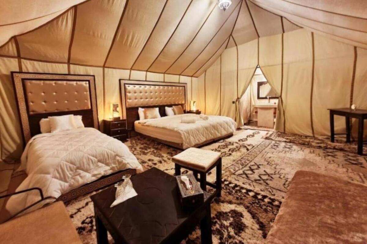 Acomodação em tenda com duas camas, uma mesa pequena e um tapete.
