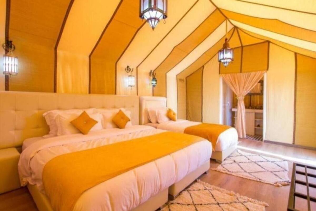 Quarto com duas camas, uma janela grande e varanda.