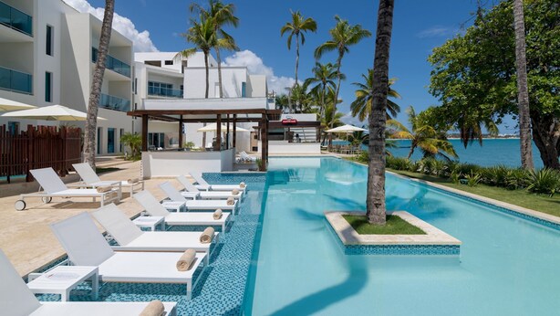 A modern resort with a pool area, sun loungers, and a view of the ocean. - 2 Bedroom Pool View, Presidential Suites Cabarete (Cabarete)