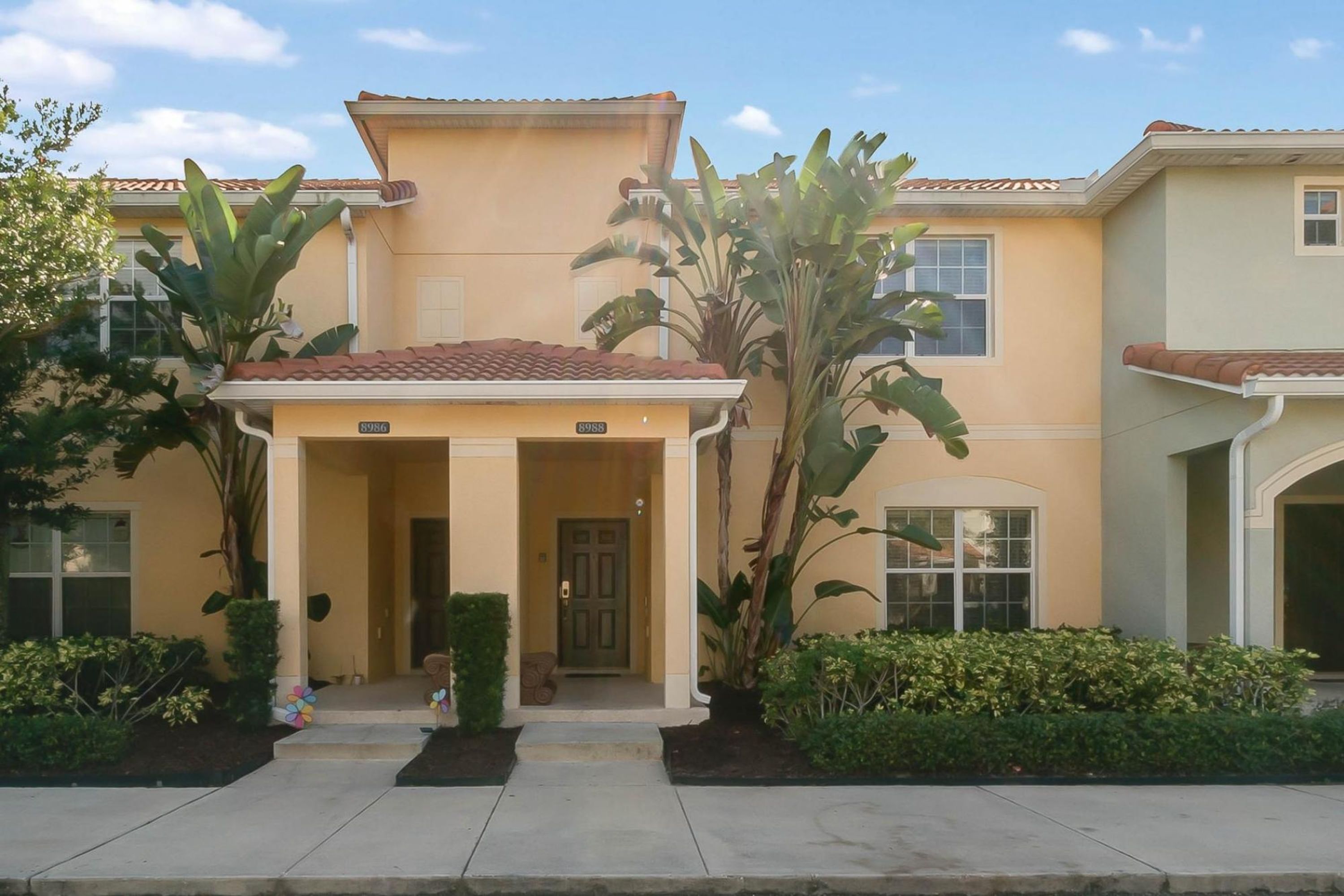 A two-story house with a covered entrance, large windows, and a tiled roof.