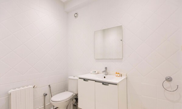 A small, white bathroom with a toilet, a sink, and a mirror. - The Perfect Flat: Sea side, central, luxurious (Marsa)