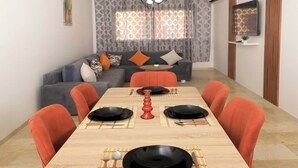 En matplats med ett långt träbord, orange klädda stolar och en modern kristallkrona.