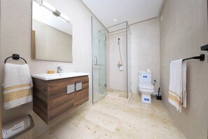 Ein modernes Badezimmer mit einer Glasdusche, einem Holzkosmetikschrank mit weißem Waschbecken und einer Toilette.